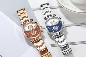 Detail of YOLAKO two-tone dial quartz watches with elegant metal link bracelets on a table