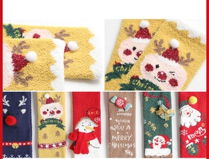 Detail von weichen Korallenvlies-Weihnachtssocken mit 3D-Pompons und festlichen Mustern