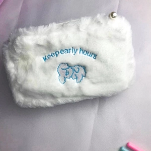 Detail of plush makeup bag with blue embroidery and elegant pearl zipper pull