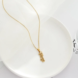 Close-up of gold stainless steel Virgo zodiac pendant necklace on a white ceramic plate