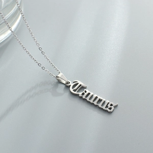 Macro shot of silver stainless steel Taurus zodiac pendant necklace on grey background
