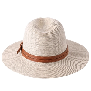 Detail of breathable woven texture and brown leather strap on cream straw jazz hat