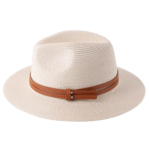 Detailed shot of beige straw hat with brown leather band and metallic rivet accents