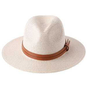 Close-up of woven straw texture and brown leather decorative band on a beige Panama hat