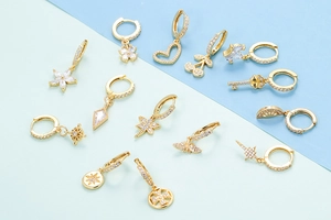 Detailed flat lay of twelve gold hoop earrings with zircon heart and butterfly pendants