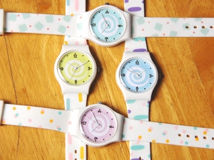 Flat lay of colorful quartz watches with polka dot patterns on a natural wood surface