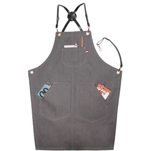 Tablier en toile grise avec lanières en cuir et poches sur fond blanc pur