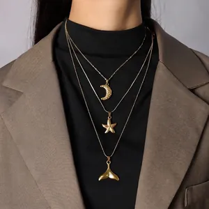 Triple layered gold necklace with moon, starfish and whale tail pendants on a model