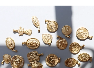 Detailansicht verschiedener 18K vergoldeter Titanstahl-Anhänger in Münz- und Herzform