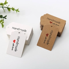 Macro view of white and kraft paper swallowtail tags with Handmade with love print