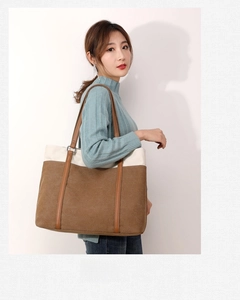 Fashionable canvas tote bag with brown leather拼接 texture shown on model in studio