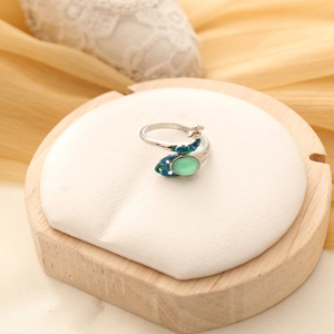 Detail of peacock ring with green gemstone and colorful enamel on silver open band