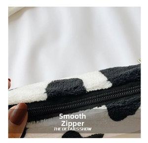 Close-up detail of smooth black nylon zipper on zebra pattern plush shoulder bag