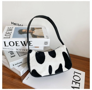 Close-up of black and white cow pattern faux fur shoulder bag with black leather strap