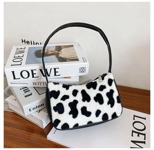 Detailed view of plush cow print baguette bag featuring black leather handle and silver zipper