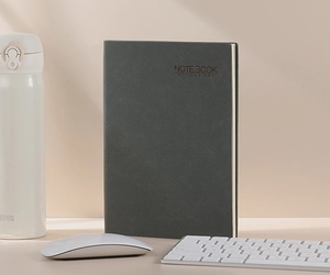 Dark grey business notebook with embossed text on desk with office accessories