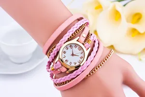 Detailed shot of pink multilayer braided wrap watch with golden chain on lady's wrist