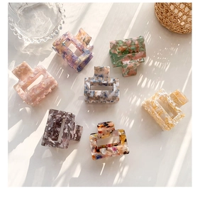 Macro shot of square acetate hair claws with floral patterns and marble texture