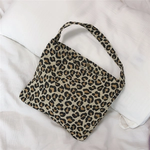 Detail of leopard print canvas bag showing the metal snap button closure and wide strap