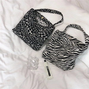Detail view of leopard and zebra print tote bags showing the metal magnetic closure