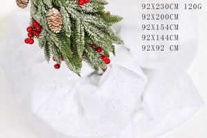Detail of white plush Christmas faux snow carpet with pine cones and red berries