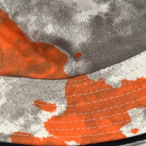 Detailed close-up of double-stitched seams and orange graffiti print on cotton bucket hat
