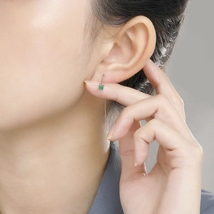 Close-up of s925 silver threader earring featuring a green square gemstone on model