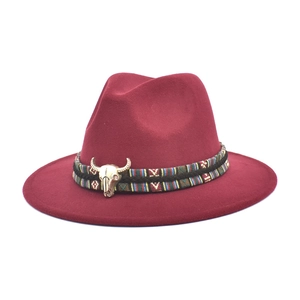 Detail of wine red fedora hat featuring ethnic woven band and golden bull skull ornament