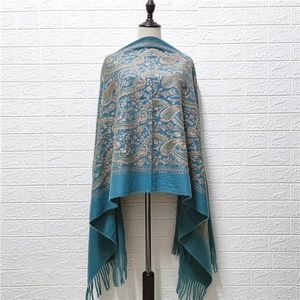 Detail view of blue cashmere-like shawl with gold paisley embroidery and elegant tassels