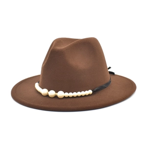 Detail of dark brown wool fedora hat featuring a white pearl band and elegant black ribbon