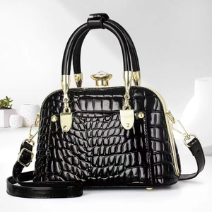 Detail of black faux crocodile leather handbag with gold hardware and jewel lock