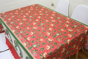 Detail of red and green Christmas tablecloth with festive bells and holly leaf patterns