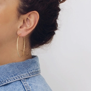 Close-up of oversized gold hoop earrings with polished finish worn by a model