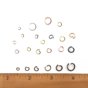 Assorted jewelry open jump rings in various colors and sizes on a measuring wooden ruler