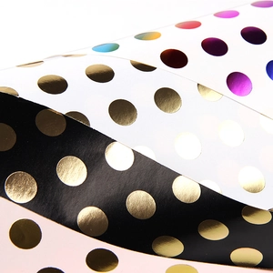 Golden and iridescent polka dot gift wrapping paper rolls for various festive occasions