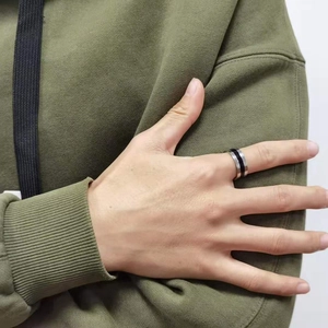 Close-up of a silver stainless steel men's ring with a black enamel inlay on a male hand