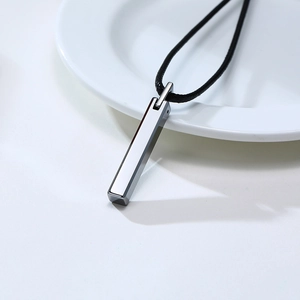 Macro shot of silver tungsten steel bar pendant on a black cord necklace