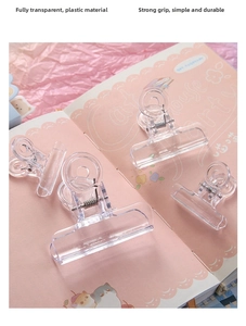 Dettaglio di clip in plastica trasparente di varie dimensioni su un taccuino rosa