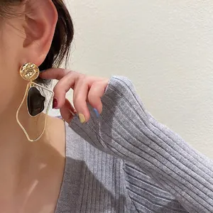 Minimalist black and gold irregular drop earrings worn by a model in a side profile view