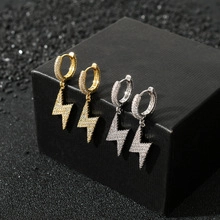 Détail macro de boucles d'oreilles créoles dorées et argentées avec éclair en zircon