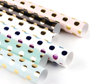 Macro view of assorted colorful gift wrapping paper rolls with gold foil polka dots