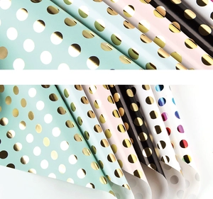 Macro detail of polka dot gift wrap with gold foil metallic finish on various paper colors