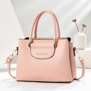 Pink litchi texture women handbag with gold hardware on minimalist display stands
