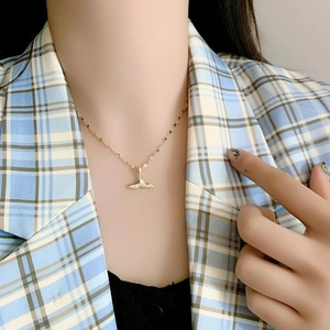 Detailed view of an elegant golden fishtail pendant necklace with sparkling zircons on neck