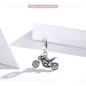 Macro shot of silver motorcycle pendant showing detailed engine and wheel mechanics