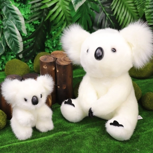 Due peluche di koala bianchi di diverse dimensioni su legno naturale e muschio verde
