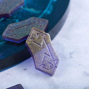 Detailed close-up of purple and gold glitter resin rune stones with engraved symbols