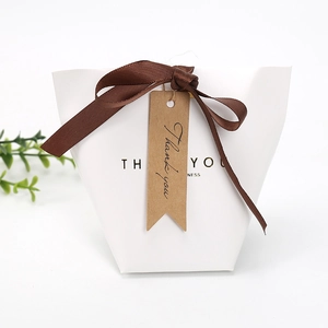 White trapezoidal gift box with brown ribbon bow and Thank You kraft paper tag label