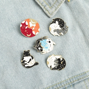 Detail view of five cartoon animal enamel pins with yin yang patterns on denim fabric
