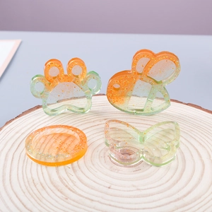 Detailed view of DIY resin molds in cat paw and bee shapes with gold glitter on wood